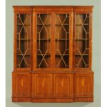 A George III style yew wood breakfront bookcase on cupboard base, with adjustable shelves.