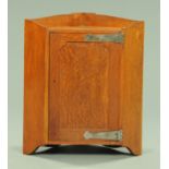 An early 20th century oak Arts & Crafts hanging corner cupboard,