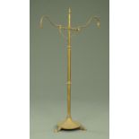 A brass lamp standard, twin branch with circular base and three short feet.