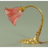 A Victorian style table lamp, with cranberry glass shade and raised on a spreading pierced foot.