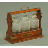 An early 20th century oak tantalus, with three cut glass decanters, width 35.5 cm.