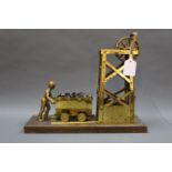 A brass mining related model, raised on a rectangular wooden plinth,