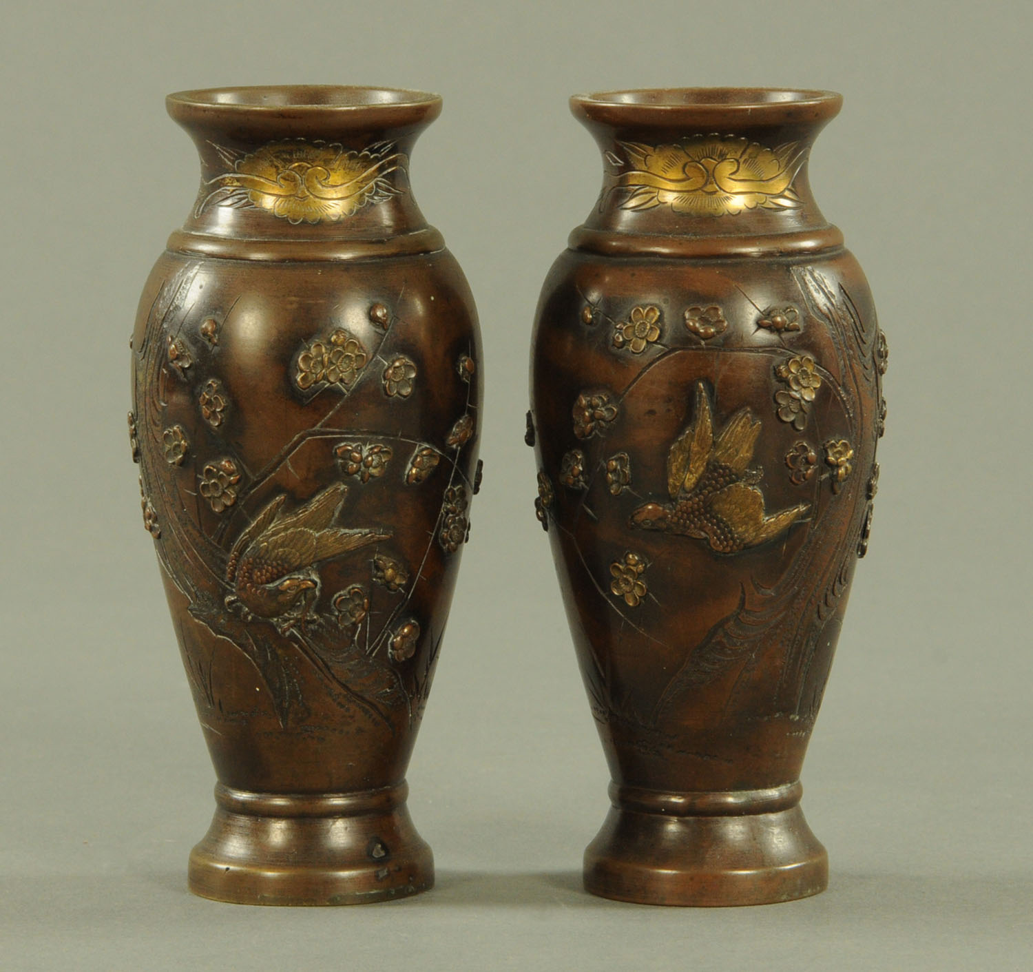 A pair of Japanese bronze vases, depicting hawks amongst blossom above a stream. Height 16 cm.