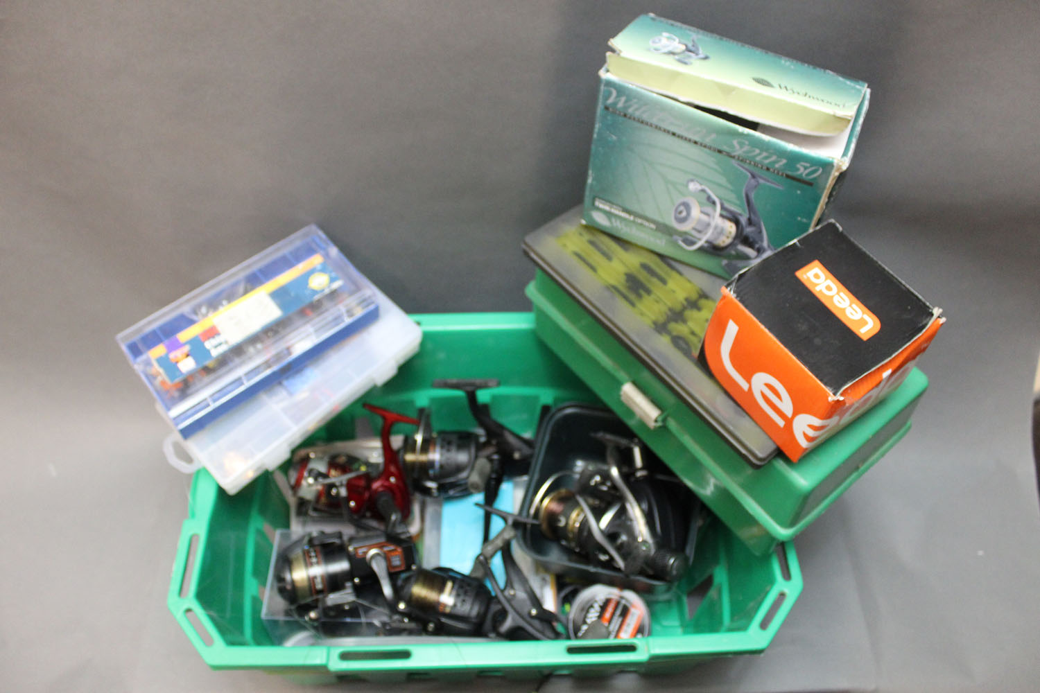 A box containing 5 fixed spool reels, various tackle boxes filled with mepps,