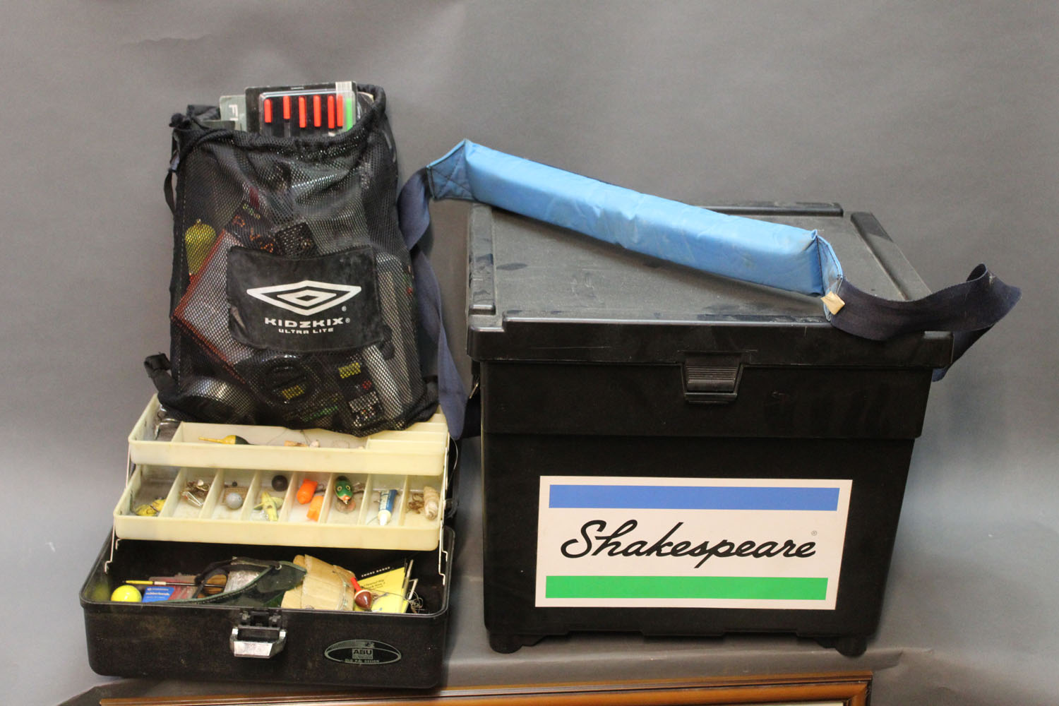 A Shakespeare fishing box/seat filled with tackle, tackle box and bag of tackle.