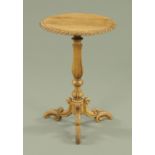 A Victorian oak tripod table, having a gadrooned border upon a carved and turned stem,