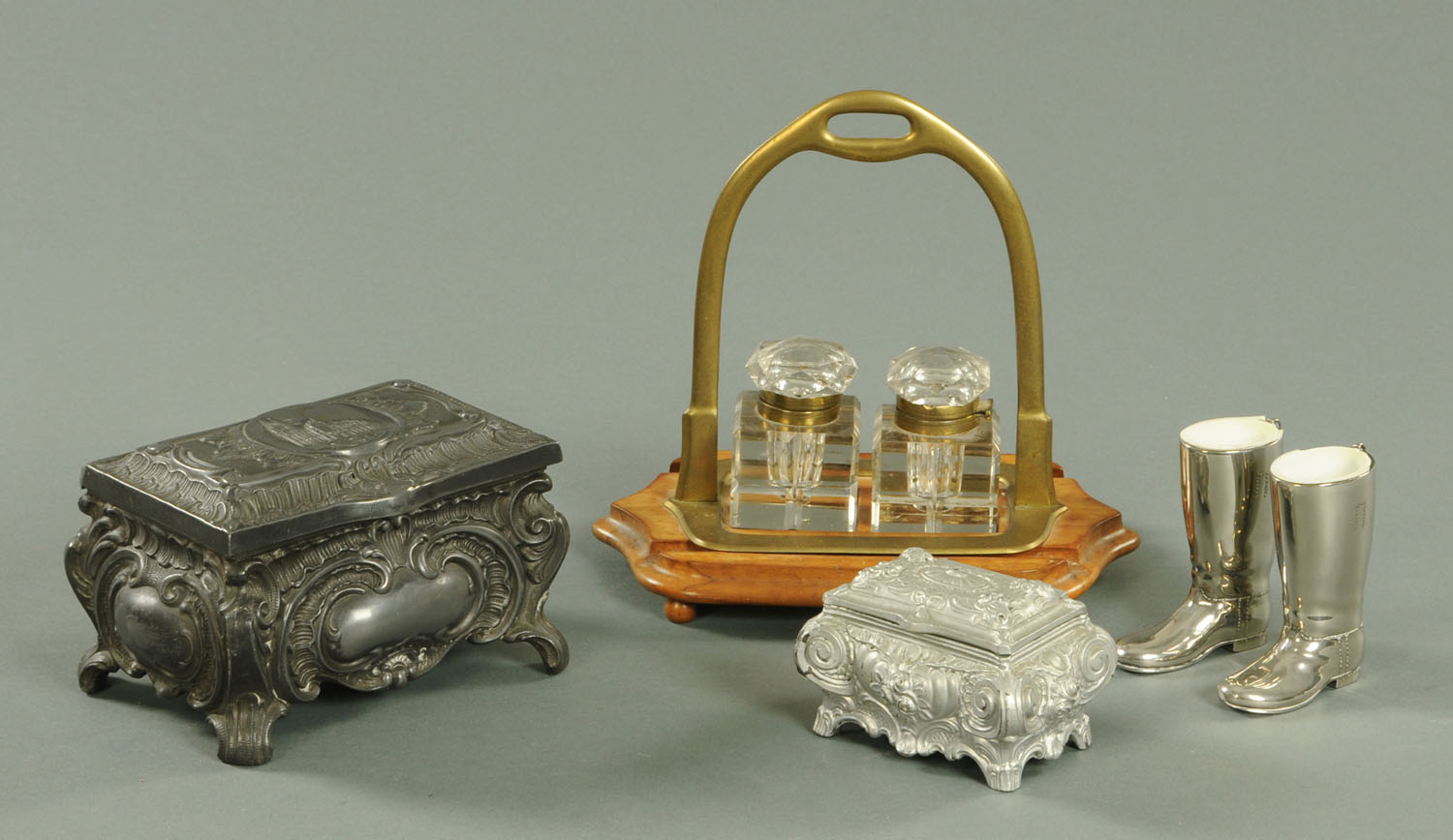 A Brass stirrup mounted inkwell with two glass bottles, all on an olive wood base with bun feet,