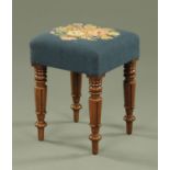 A Victorian mahogany footstool, with woolwork tapestry top and raised on stylised tulip carved legs.