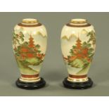 A pair of Japanese Satsuma vases, circa 1920, depicting a mountainous landscape with buildings,