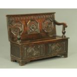 An 18th century carved oak box settle, the three panel back with later Victorian face mask carvings,