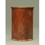 A small mahogany bow front wall mounted corner cabinet,