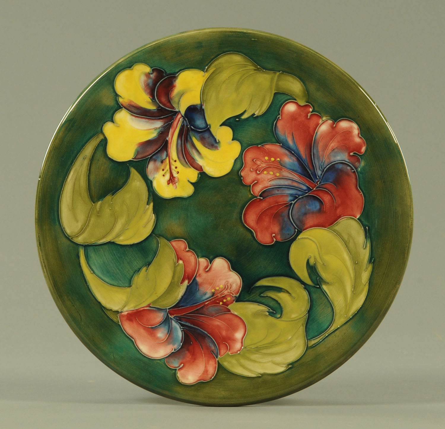 A Walter Moorcroft "Hibiscus" pattern charger, mid 20th century, with green ground,