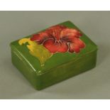 A Moorcroft hibiscus pattern trinket box and cover, mid 20th century, against a sage green ground,