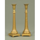 A pair of Egyptian Revival style cast brass candlesticks,