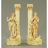 A pair of Royal Dux figures, each standing by a pillar and with pink triangle mark to base.