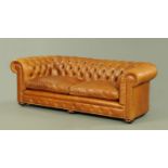 A Victorian style leather Chesterfield settee, deep buttoned and with two loose cushions,