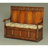 An 18th century style oak box settle, having an arcaded top rail above a four panel back,