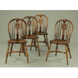 A set of four oak Windsor style dining chairs, with solid seats and crinoline stretchers.