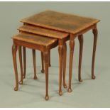A nest of three walnut veneered occasional tables, with cabriole legs terminating in pad feet.
