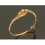A 9 ct gold hinged bangle set with three opals, interior diameter 6 cm,