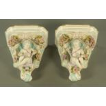 A pair of 19th century Emile Claus porcelain wall brackets, cherubs with garlands of flowers.