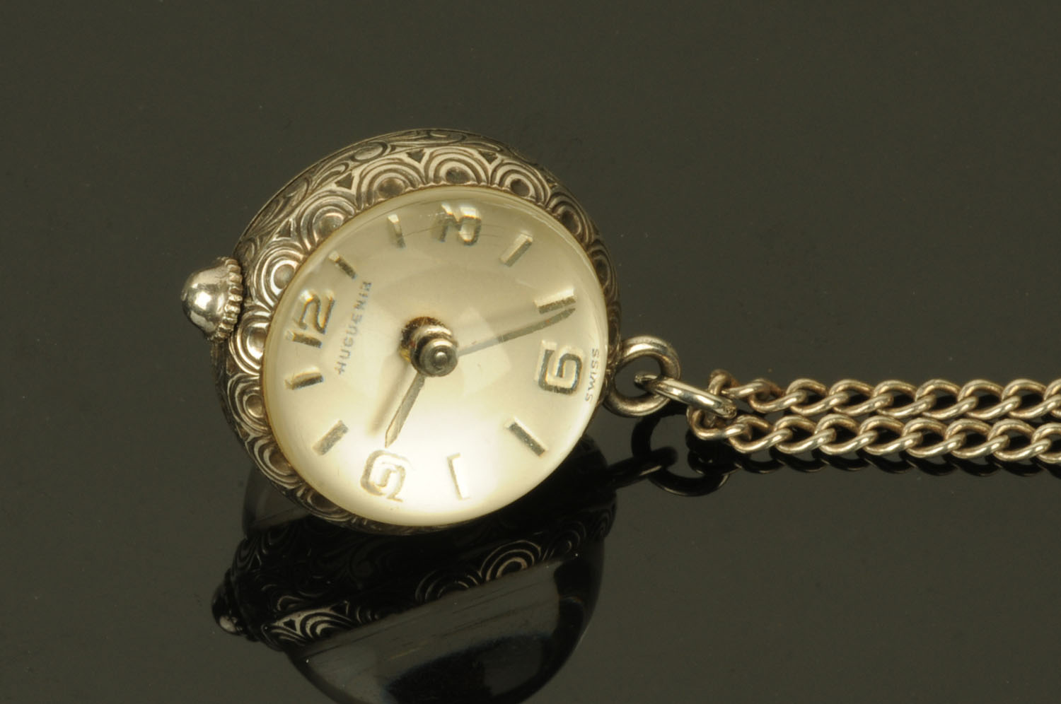 A silver pendant ball watch by Huguenin, on silver chain.