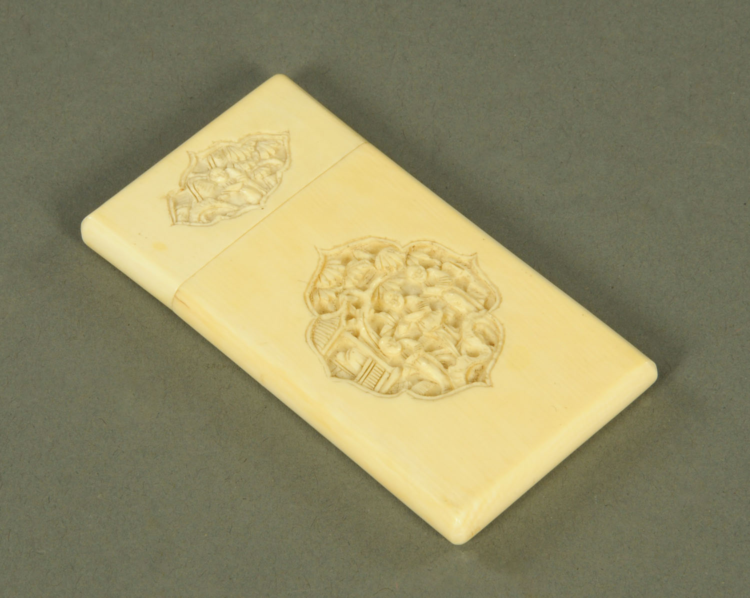 A Canton carved ivory card case, circa 1880, each side with two shaped cartouches depicting figures,