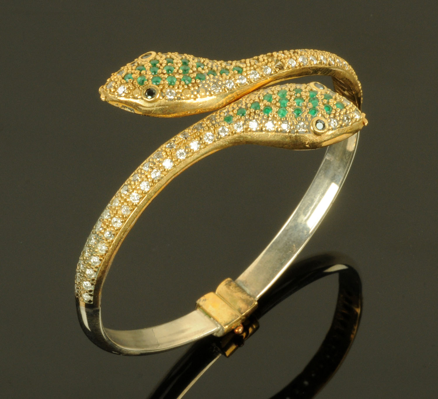 A snake bangle, set with green, blue and clear stones and with sprung mechanism.