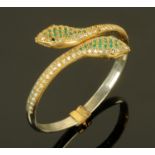 A snake bangle, set with green, blue and clear stones and with sprung mechanism.