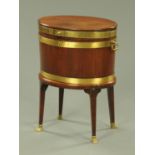 A Georgian mahogany oval wine cooler, the brass banded hinged top above the oval coopered body,