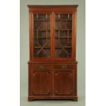An Edwardian mahogany bookcase on cupboard, with astragal glazed doors enclosing adjustable shelves,