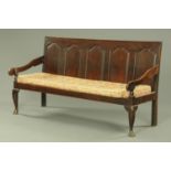 A George III oak five panelled settle, with silhouette arms and squab cushion,