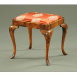A Queen Anne style walnut stool, with drop in seat and raised on shell carved cabriole legs.