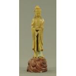 A Chinese soapstone carving of Guanyin, early 20th century, standing on a scrolling base,