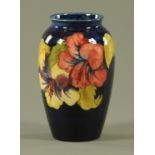A Walter Moorcroft "Hibiscus" pattern vase, with dark blue ground, with inscribed initials,