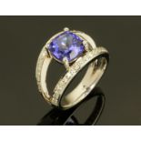An 18 ct white gold ring with cushion cut tanzanite to diamond set split shank, total weight +/- 3.