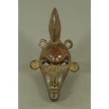 A Benin bronze tribal wall mask, depicting a stylised tribal figure. 27 cm long.