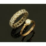 A 9 ct white gold paste set eternity ring, size L/M, and a gold coloured ring set with a pearl,