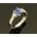 An 18 ct white gold ring set with an oval tanzanite with trefoil of diamonds to each shoulder,