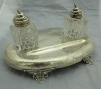 A Victorian silver desk standish of oval form, raised on four acanthus leaf style feet,