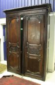 A 19th Century French oak armoire with carved cornice over two carved fielded panelled doors