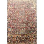 A Krisnan carpet, the central panel set with all over floral decoration on a dark red ground,
