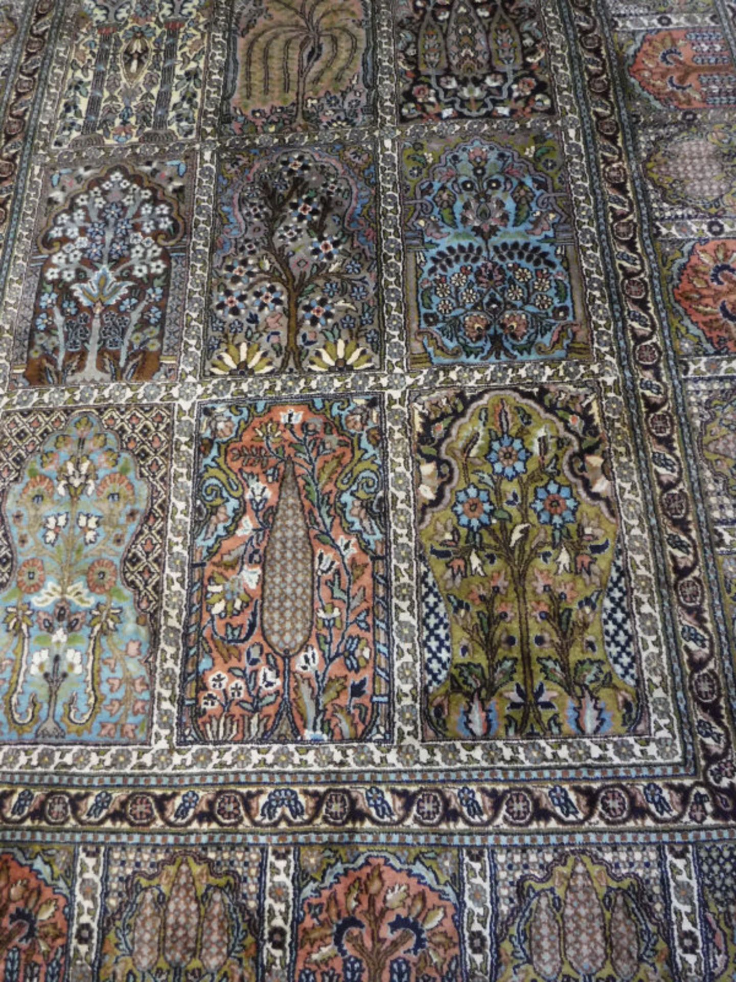 A Persian carpet, the central panel set with tiled pattern, each tile set with a floral design,