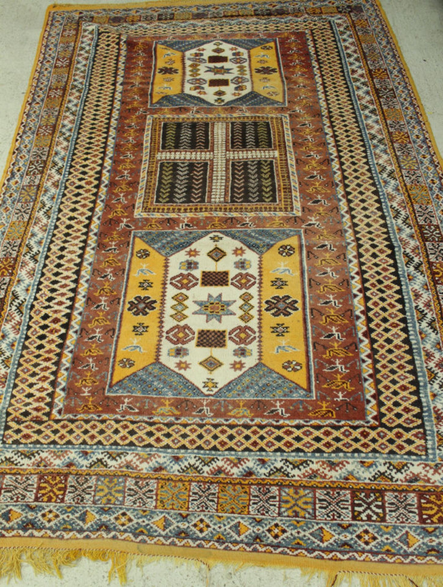 A Caucasian rug, the central panel set with repeating square medallions on a terracotta ground, - Bild 2 aus 2