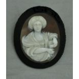 A Victorian carved shell cameo brooch depicting a lady with scroll in middle eastern dress within a