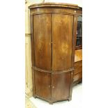 An early 19th Century elm free-standing corner cupboard with two pairs of bow fronted doors