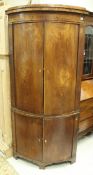 An early 19th Century elm free-standing corner cupboard with two pairs of bow fronted doors