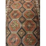 A Kazak rug, the central panel set with repeating medallions on a dark black ground,