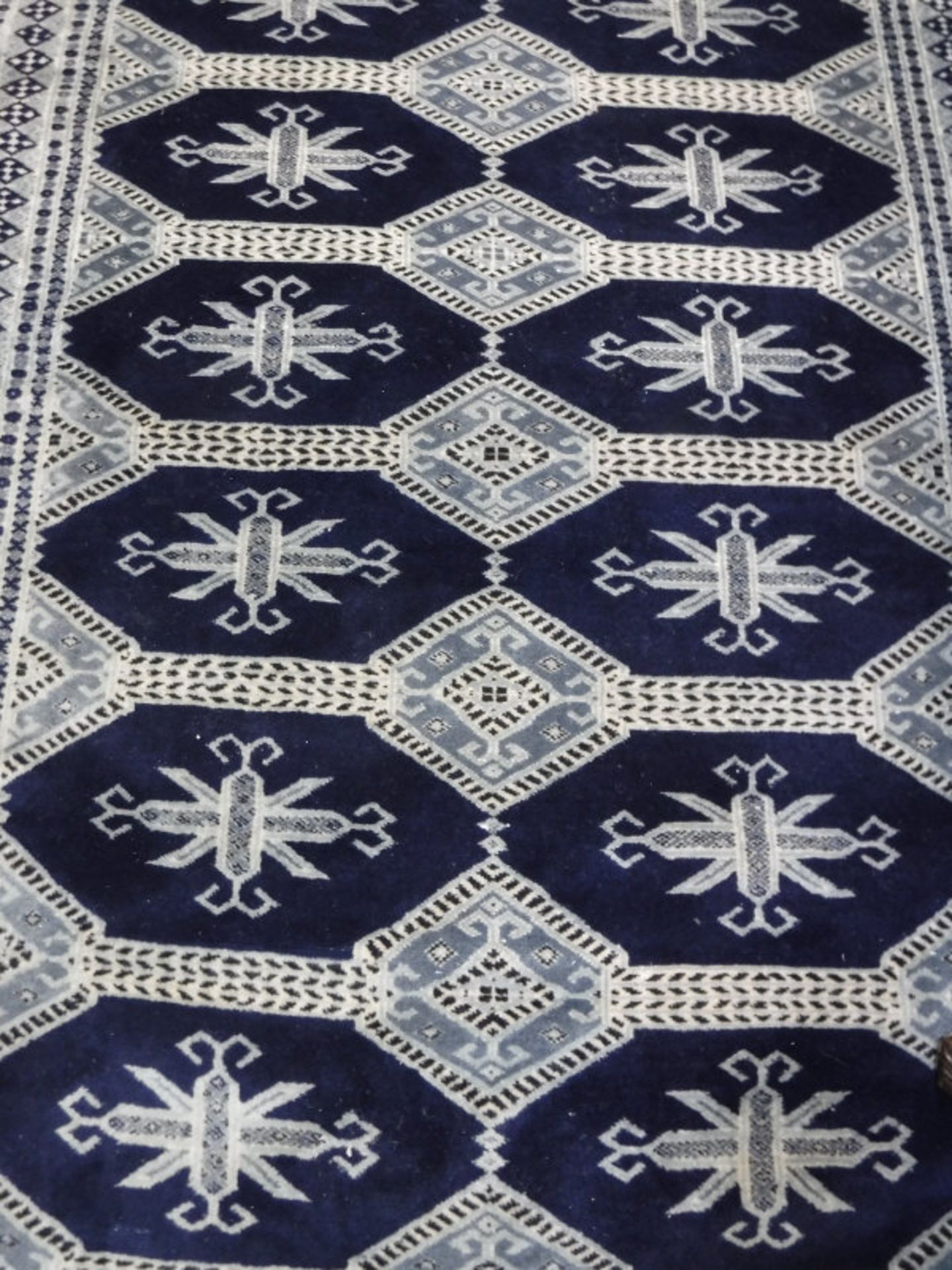 A Persian rug, the central panel set with repeating medallions on a dark blue ground,