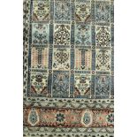 An Eastern carpet, the central panel set with repeating floral decorated tile design,